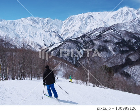 岩岳スノーフィールド山頂付近から未圧雪エリアを行くスキーヤーと白馬連峰を望む 岩岳スノーフィールド山頂付近から未圧雪エリアを行くスキーヤーと白馬連峰を望む 130995126