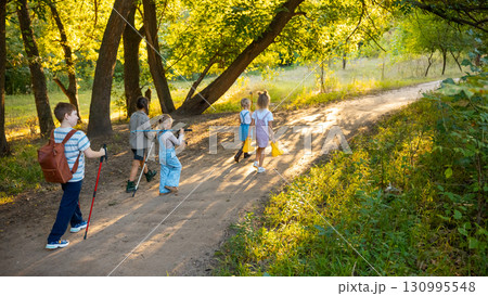 Group of children hiking forest path with sunlight shining through trees Group of children hiking forest path with sunlight shining through trees 130995548