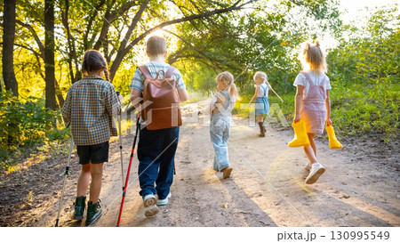 Children walking with yellow boots in hands along forest trail 130995549