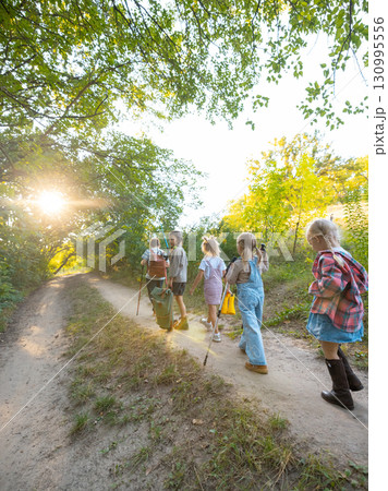 Children hiking on sandy path in forest under sunlight Children hiking on sandy path in forest under sunlight 130995556