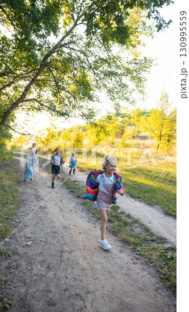 Children running joyfully on sunny forest path during outdoor adventure 130995559