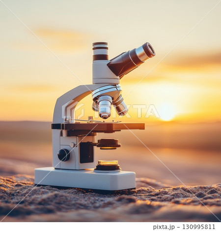 Microscope on sandy surface with sunset in the background 130995811
