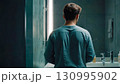 Young Man Looking in Mirror in Bathroom 130995902