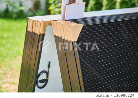 Close-up new solar panels with protective cardboard corners, ready for installation. Renewable energy technology, green living, and the implementation of solar power in residential areas. 130996224