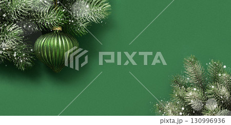 Christmas green bauble on fir snowy branch and lights garland on green background. Xmas greeting card. New Year banner. Copy space. View from above. Christmas green bauble on fir snowy branch and lights garland on green background. Xmas greeting card. New Year banner. Copy space. View from above. 130996936