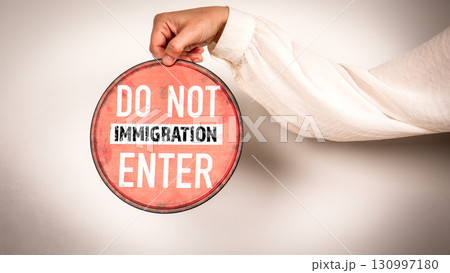 Hand holding red do not enter immigration sign 130997180