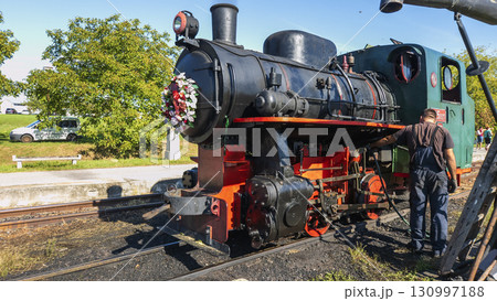 Nitra, Slovakia - September 4, 2025: A worker maintains a vintage steam locomotive on display at the Nitra Agricultural University. 130997188