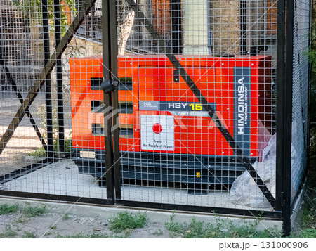 Dnipro, Ukraine - June 28, 2024: Diesel generator to support the operation of the boiler room of a residential apartment building during a power outage in cold weather. Dnipro, Ukraine - June 28, 2024: Diesel generator to support the operation of the boiler room of a residential apartment building during a power outage in cold weather. 131000906