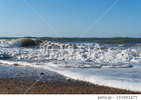 Beautiful blue sea and large calm waves and foam. Wave splashing over pebbles at sea. Rolling ocean waves. Summer paradise beach background. Powerful sea waves Beautiful blue sea and large calm waves and foam. Wave splashing over pebbles at sea. Rolling ocean waves. Summer paradise beach background. Powerful sea waves 131001075