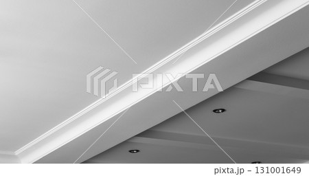 Suspended and grid ceiling with LED spots lamps and drywall construction in empty room in house interior. Stretch ceiling white and complex shape. 131001649