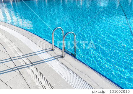 Swimming pool with stair and water. Swimming pool with handrail. Stainless steel ladder in pool. Grab bars ladder in the blue swimming pool 131002039