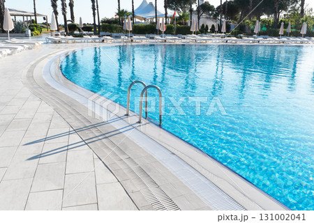 Swimming pool with stair and water. Swimming pool with handrail. Stainless steel ladder in pool. Grab bars ladder in the blue swimming pool 131002041