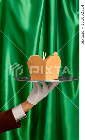 Brown blank takeout box with chopsticks on tray held by waiter in glove against green curtain Brown blank takeout box with chopsticks on tray held by waiter in glove against green curtain 131002514