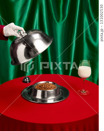 Elegant serving of pet food bowl and glass of milk on red table with green fabric background 131002530