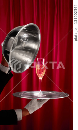 Elegant champagne glass served on silver tray with red curtain background 131002544