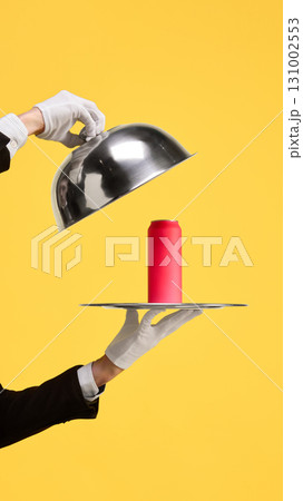 Silver cloche unveiling red mockup can on tray against yellow background 131002553