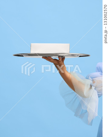 Child hand in blue dress presenting silver tray with white gift box Child hand in blue dress presenting silver tray with white gift box 131002570
