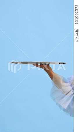 Hand of child in blue dress holding empty silver serving tray on pastel background. Negative space for ads Hand of child in blue dress holding empty silver serving tray on pastel background. Negative space for ads 131002572