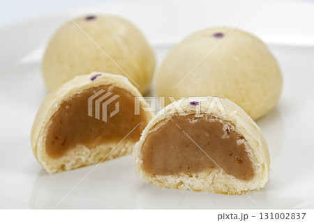 Taro mooncake Chinese pastry flaky crust sweet taro filling round dessert traditional snack white plate close up delicious treat Asian bakery Taro mooncake Chinese pastry flaky crust sweet taro filling round dessert traditional snack white plate close up delicious treat Asian bakery 131002837