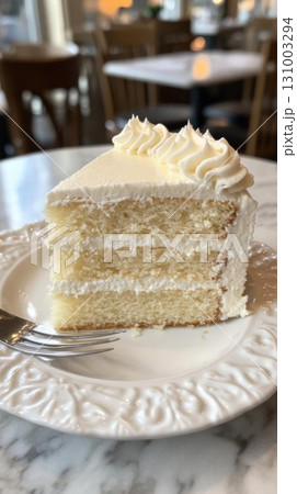 Piece of Cream cake on a white plate with a fork in the background. 131003294