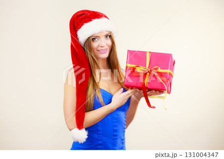 Woman in santa claus hat holds gift box. Christmas time Woman in santa claus hat holds gift box. Christmas time 131004347