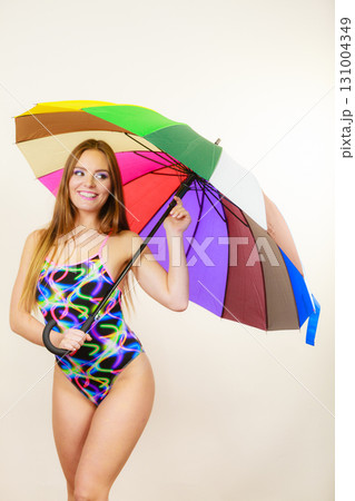 Happy woman posing in swimsuit and colorful umbrella Happy woman posing in swimsuit and colorful umbrella 131004349