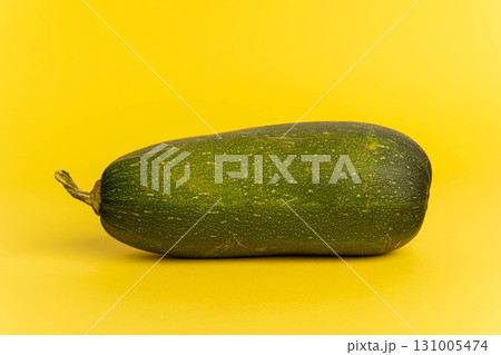 Green zucchini vegetable lying on yellow background 131005474