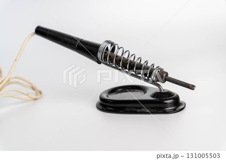 Vintage soldering iron resting on a metal stand Vintage soldering iron resting on a metal stand 131005503