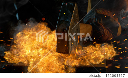Close-up of blacksmith forging glowing hot iron on anvil with flying sparks Close-up of blacksmith forging glowing hot iron on anvil with flying sparks 131005527