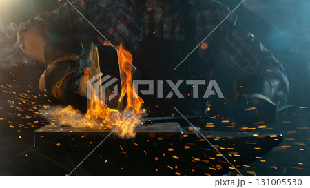 Close-up of blacksmith forging glowing hot iron on anvil with flying sparks Close-up of blacksmith forging glowing hot iron on anvil with flying sparks 131005530