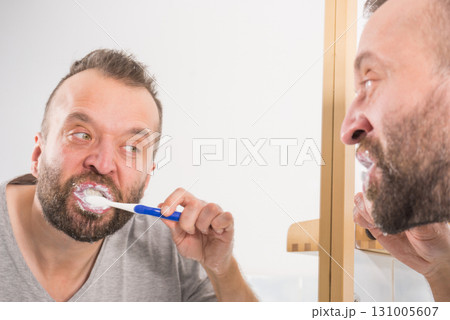 Man brushing his teeth in bathroom Man brushing his teeth in bathroom 131005607