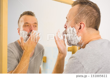 Guy shaving his beard in bathroom Guy shaving his beard in bathroom 131005611