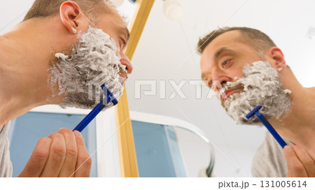 Guy shaving his beard in bathroom Guy shaving his beard in bathroom 131005614