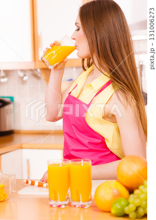 Woman in kitchen drinking fresh orange juice Woman in kitchen drinking fresh orange juice 131006273