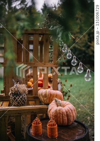 Decorative autumn display featuring pumpkins and string lights in a cozy outdoor setup 131006729