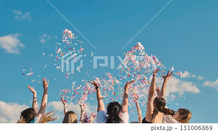 Students celebrating their graduation by tossing colorful confetti into the summer sky 131006869