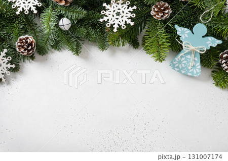 Christmas frame with evergreen branches and angel of wooden natural materials, snowflakes on white background. Copy space. Xmas greeting card. Winter Holiday. View from above. 131007174