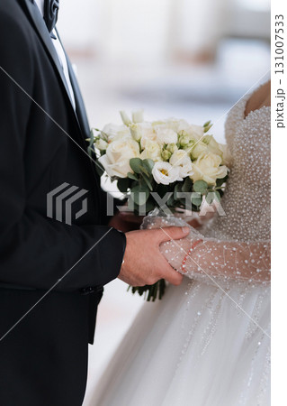 Elegant bride and groom holding wedding bouquet and hands on their wedding day 131007533
