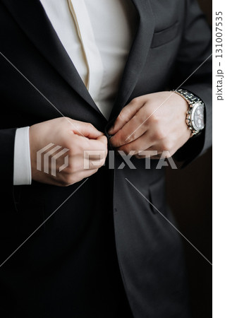 Elegant man buttoning black suit jacket, close up of hands and luxury watch Elegant man buttoning black suit jacket, close up of hands and luxury watch 131007535