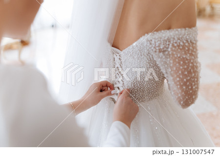 Bridal dress back lacing close up on wedding morning preparation moment Bridal dress back lacing close up on wedding morning preparation moment 131007547