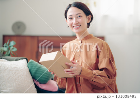 通販で購入した商品を持つ40代の日本人女性 131008495