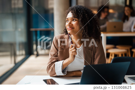 A thoughtful and professional woman engaged in her work in a modern and inspiring workspace 131008625