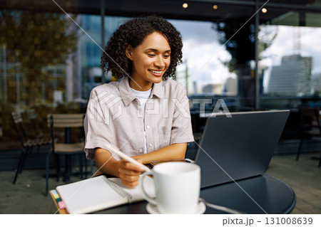 A Young Woman Engaged in Productive Work on Her Laptop at a Charming and Cozy Cafe Setting A Young Woman Engaged in Productive Work on Her Laptop at a Charming and Cozy Cafe Setting 131008639