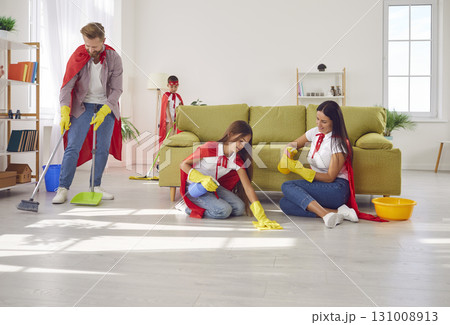 Parents and children in red superhero capes are doing domestic chores all together 131008913