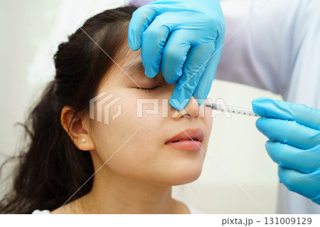 Asian woman receiving plastic surgery shape of nose performed on face. Asian woman receiving plastic surgery shape of nose performed on face. 131009129