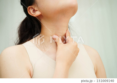Asian woman touching her neck and throat for thyroid gland problem. Asian woman touching her neck and throat for thyroid gland problem. 131009140