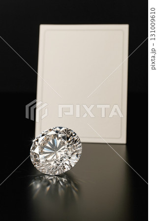 Round cut diamond on reflective surface with blank card background 131009610