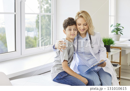 Happy Female Doctor Or Nurse Embracing Young Boy During Hospital Consultation 131010615