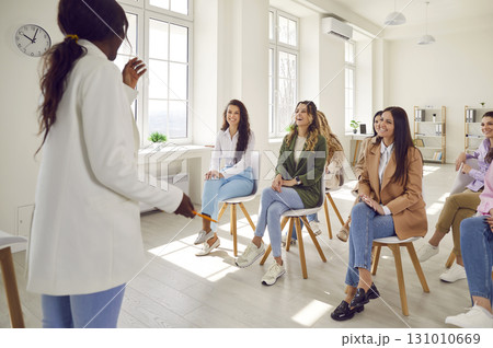 Happy diverse women laughing at funny joke that coach shares during business presentation 131010669