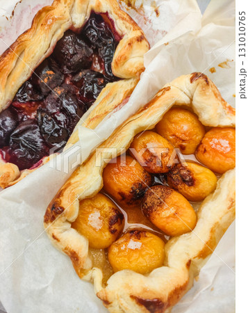 Delicious homemade apricot and plum tarts baking on parchment paper Delicious homemade apricot and plum tarts baking on parchment paper 131010765